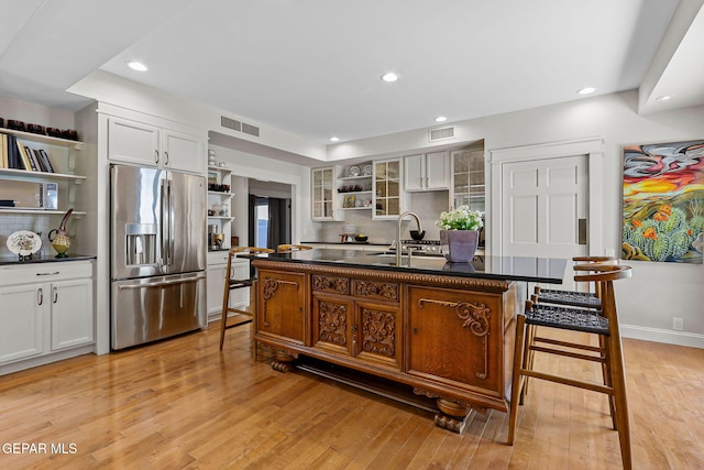 1119 Los Jardines Cir, El Paso, TX 79912 - kitchen featuring open shelves, stainless steel fridge with ice dispenser, dark countertops, light wood-style floors, and decorative backsplash