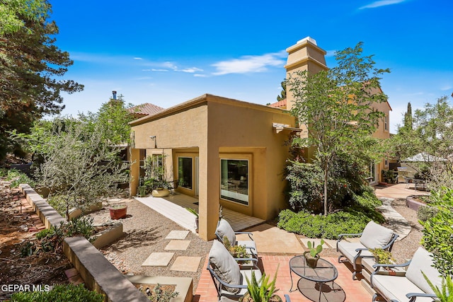 1119 Los Jardines Cir, El Paso, TX 79912 - back of house with a patio, stucco siding, a chimney, and an outdoor living space