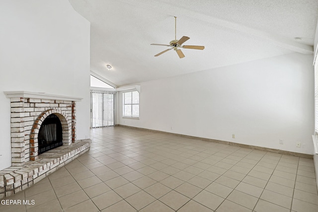 7145 Golden Hawk Dr, El Paso, TX 79912 - unfurnished living room featuring ceiling fan, vaulted ceiling, light tile patterned floors, a textured ceiling, and a brick fireplace
