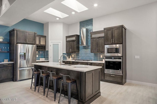 2212 Mike Price Dr, El Paso, TX 79938 - kitchen with appliances with stainless steel finishes, a skylight, a breakfast bar area, dark brown cabinetry, and backsplash