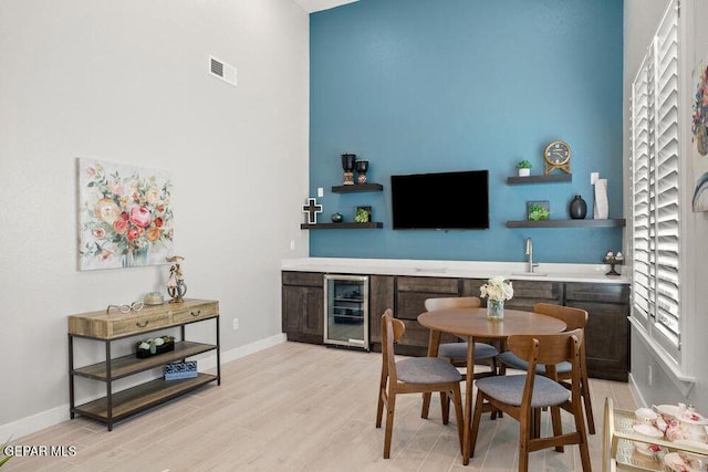 2212 Mike Price Dr, El Paso, TX 79938 - dining room with wine cooler, bar area, light wood finished floors, and a towering ceiling