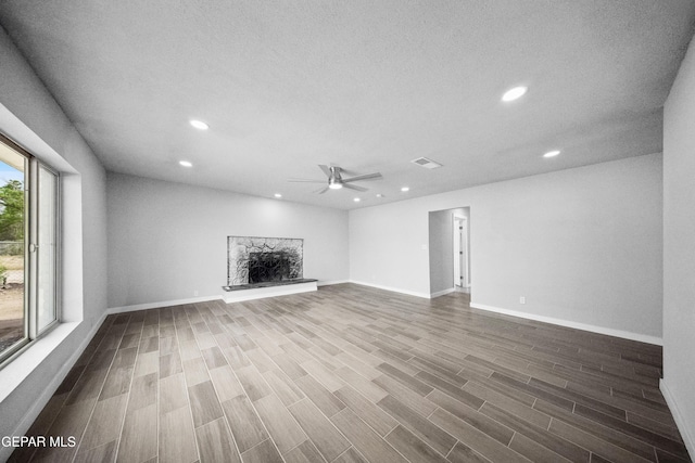10950 Jo Way, Socorro, TX 79927 - unfurnished living room featuring recessed lighting, a ceiling fan, a stone fireplace, wood finished floors, and baseboards