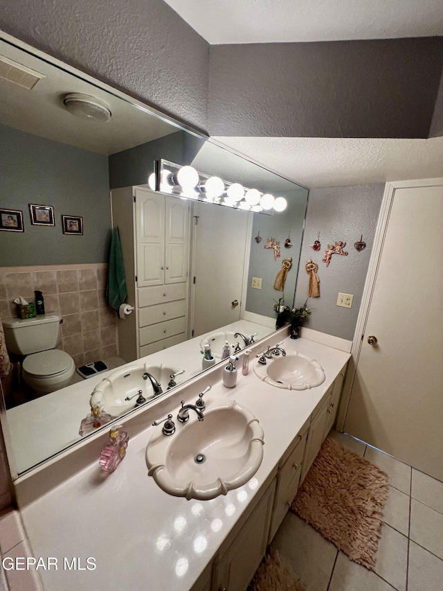 16899 Old Butterfield Trl, El Paso, TX 79938 - bathroom featuring tile patterned flooring, double vanity, wainscoting, tile walls, and a textured ceiling