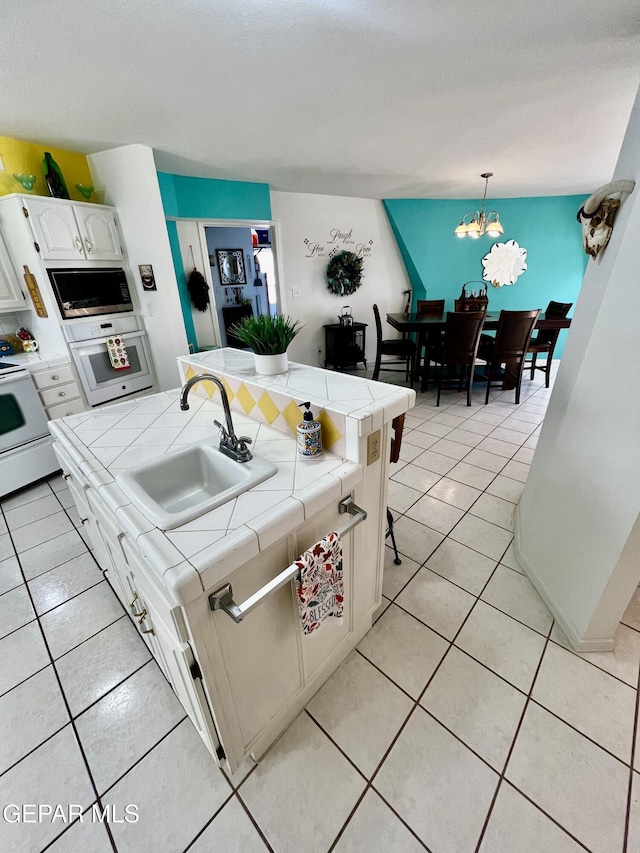 16899 Old Butterfield Trl, El Paso, TX 79938 - kitchen featuring tile countertops, white appliances, light tile patterned floors, white cabinetry, and a chandelier