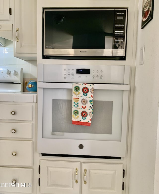 16899 Old Butterfield Trl, El Paso, TX 79938 - kitchen view of stainless steel microwave, white oven, white cabinetry, and light countertops