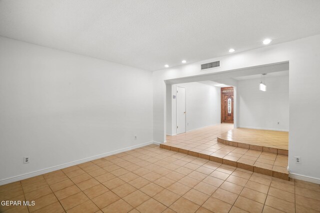 10601 Groverock Ct, El Paso, TX 79935 - empty room featuring recessed lighting, light tile patterned floors, arched walkways, a textured ceiling, and baseboards