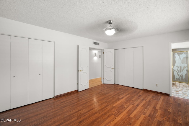 10601 Groverock Ct, El Paso, TX 79935 - unfurnished bedroom with multiple closets, wood finished floors, a textured ceiling, ceiling fan, and ensuite bathroom