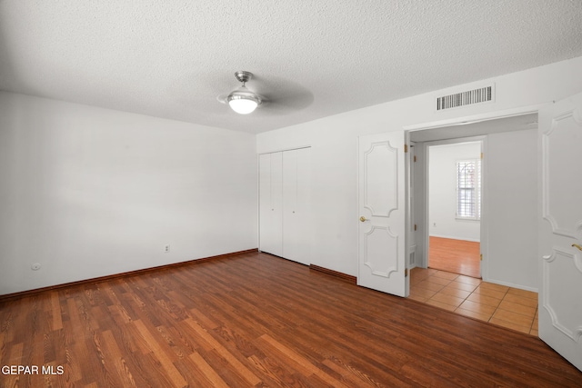 10601 Groverock Ct, El Paso, TX 79935 - unfurnished bedroom featuring wood finished floors, a textured ceiling, a closet, a ceiling fan, and baseboards
