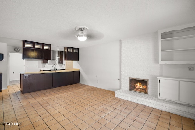 10601 Groverock Ct, El Paso, TX 79935 - kitchen featuring open floor plan, a peninsula, a sink, glass insert cabinets, and light countertops