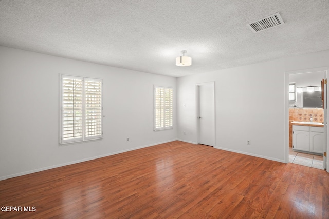 10601 Groverock Ct, El Paso, TX 79935 - unfurnished room with healthy amount of natural light, wood finished floors, a textured ceiling, and baseboards