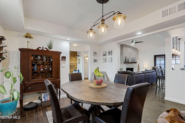 840 Tepic Dr, El Paso, TX 79912 - dining area featuring dark wood-style floors, a ceiling fan, a large fireplace, baseboards, and a textured ceiling