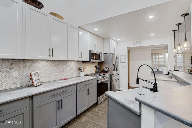 840 Tepic Dr, El Paso, TX 79912 - kitchen with stainless steel appliances, gray cabinets, decorative backsplash, light countertops, and pendant lighting
