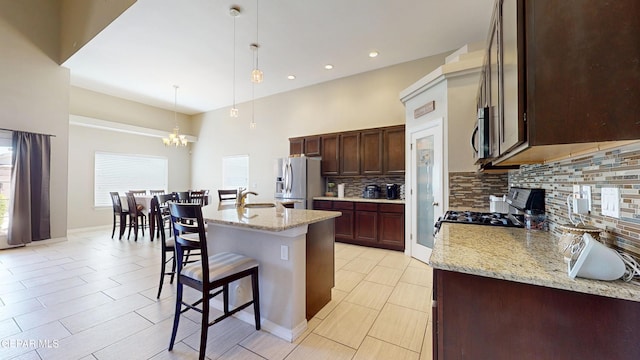 5712 Valley Lilac Ln, El Paso, TX 79932 - kitchen featuring appliances with stainless steel finishes, backsplash, a chandelier, a kitchen breakfast bar, and pendant lighting