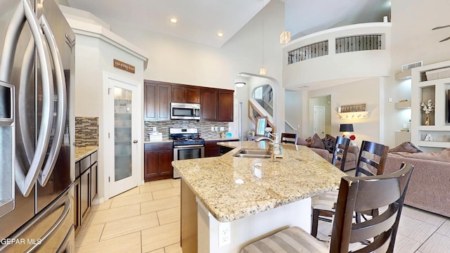 5712 Valley Lilac Ln, El Paso, TX 79932 - kitchen with appliances with stainless steel finishes, open floor plan, a sink, a kitchen bar, and tasteful backsplash
