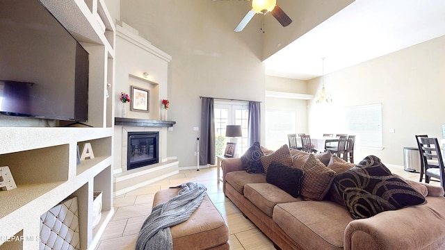 5712 Valley Lilac Ln, El Paso, TX 79932 - living area with a high ceiling, a glass covered fireplace, ceiling fan, a chandelier, and baseboards