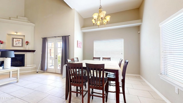 5712 Valley Lilac Ln, El Paso, TX 79932 - dining space with a chandelier, light tile patterned flooring, baseboards, a high ceiling, and a glass covered fireplace