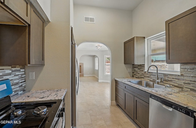 1718 Dean Jones Dr, El Paso, TX 79936 - kitchen featuring appliances with stainless steel finishes, a sink, backsplash, arched walkways, and healthy amount of natural light
