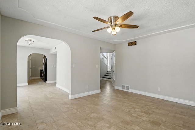 1718 Dean Jones Dr, El Paso, TX 79936 - empty room featuring arched walkways, ceiling fan, a textured ceiling, stairway, and baseboards