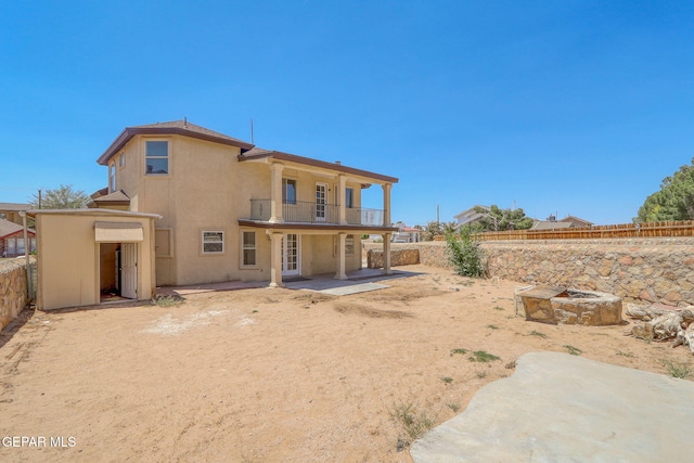 1718 Dean Jones Dr, El Paso, TX 79936 - back of property featuring a balcony, a fenced backyard, a patio area, stucco siding, and an outdoor fire pit