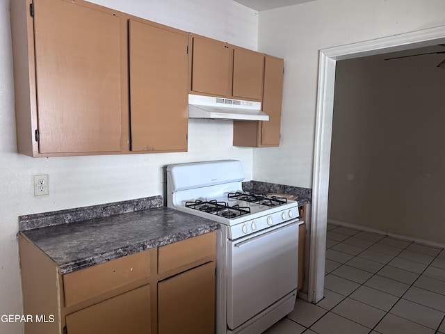 5403 Raymond Telles Rd, El Paso, TX 79924 - kitchen with under cabinet range hood, gas range gas stove, dark countertops, and light tile patterned flooring