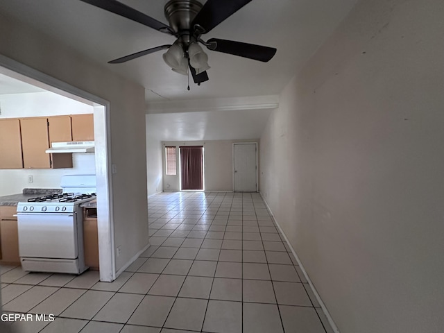 5403 Raymond Telles Rd, El Paso, TX 79924 - kitchen featuring white gas range, under cabinet range hood, light tile patterned flooring, ceiling fan, and baseboards