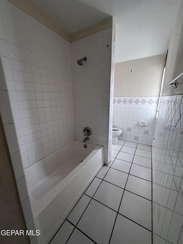 5403 Raymond Telles Rd, El Paso, TX 79924 - bathroom featuring tile patterned flooring, toilet, washtub / shower combination, and tile walls
