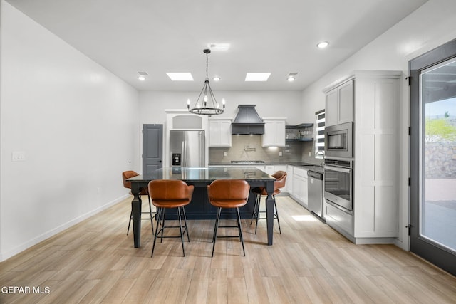 7467 Cimarron Gap Dr, El Paso, TX 79911 - kitchen featuring appliances with stainless steel finishes, custom range hood, a skylight, a kitchen breakfast bar, and decorative backsplash
