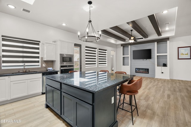 7467 Cimarron Gap Dr, El Paso, TX 79911 - kitchen featuring a sink, appliances with stainless steel finishes, a center island, white cabinets, and a breakfast bar