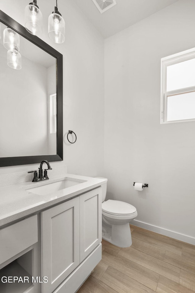 7467 Cimarron Gap Dr, El Paso, TX 79911 - half bathroom with vanity, toilet, wood finished floors, and baseboards