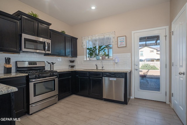 2221 Furtherpoint Pl, El Paso, TX 79911 - kitchen with appliances with stainless steel finishes, light stone counters, backsplash, dark cabinets, and recessed lighting