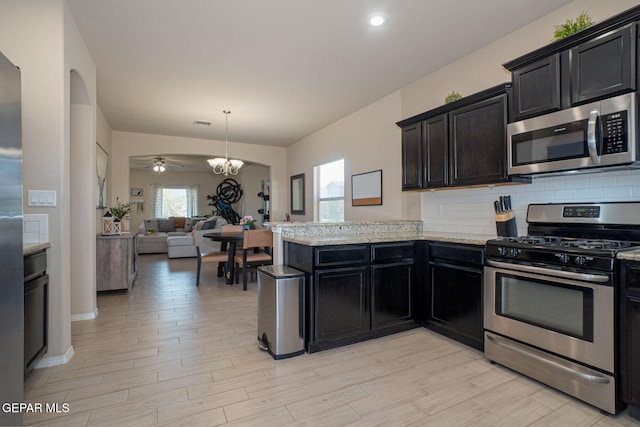 2221 Furtherpoint Pl, El Paso, TX 79911 - kitchen with stainless steel appliances, open floor plan, tasteful backsplash, a peninsula, and light wood-style flooring