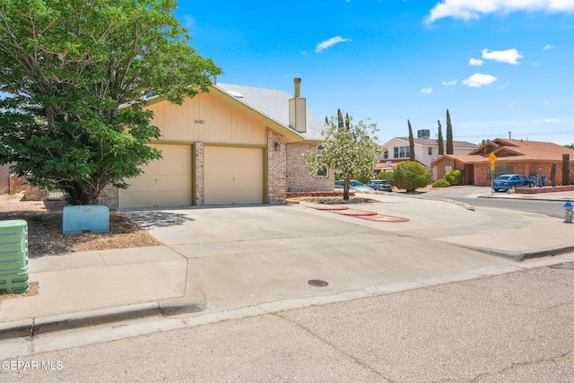 1640 Dennis Babjack Dr, El Paso, TX 79936 - obstructed view of property featuring driveway, an attached garage, a chimney, and brick siding