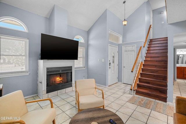 1640 Dennis Babjack Dr, El Paso, TX 79936 - living area featuring high vaulted ceiling, a warm lit fireplace, stairway, plenty of natural light, and light tile patterned floors
