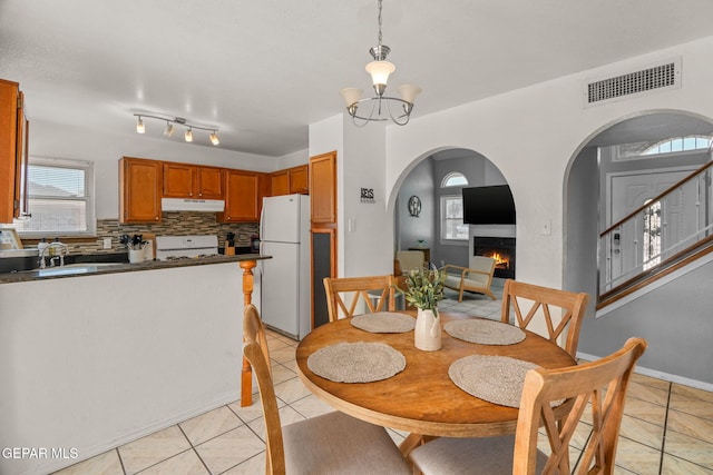 1640 Dennis Babjack Dr, El Paso, TX 79936 - dining room with light tile patterned flooring, arched walkways, a lit fireplace, and a chandelier