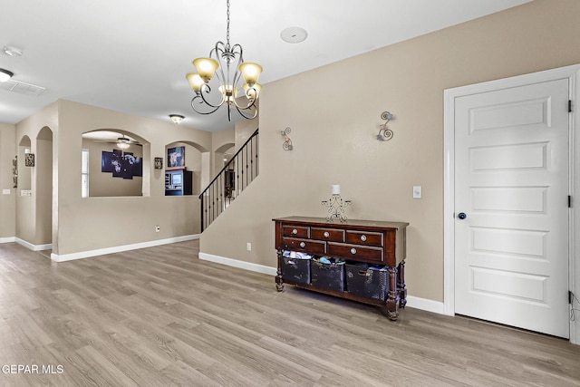 5505 Valley Cedar Dr, El Paso, TX 79932 - spare room featuring arched walkways, light wood-style floors, baseboards, stairs, and a chandelier