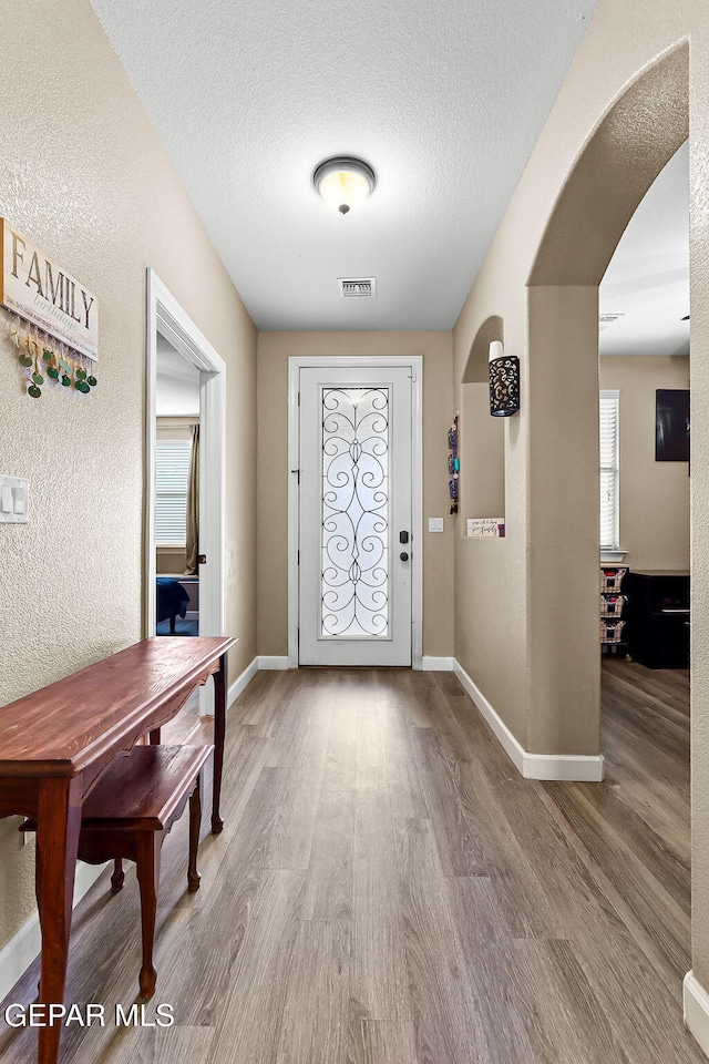 5505 Valley Cedar Dr, El Paso, TX 79932 - entryway with arched walkways, wood finished floors, baseboards, and a textured ceiling