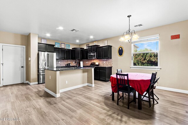 5505 Valley Cedar Dr, El Paso, TX 79932 - kitchen featuring stainless steel appliances, dark cabinetry, light wood-type flooring, a chandelier, and tasteful backsplash