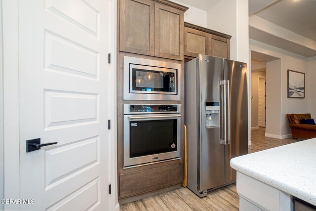 13436 Emerald Crystal Dr, El Paso, TX 79928 - kitchen featuring appliances with stainless steel finishes, light wood-type flooring, light stone counters, and baseboards
