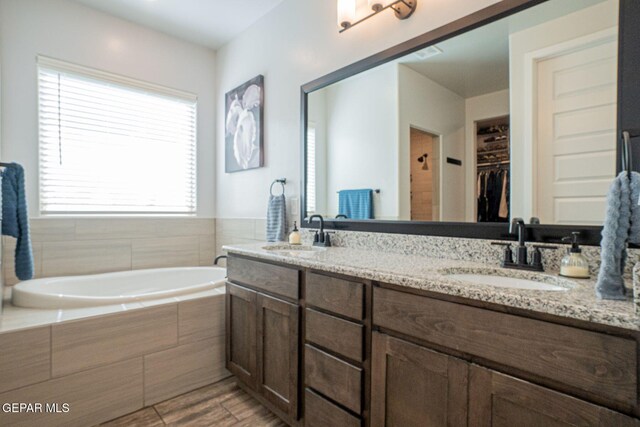 13436 Emerald Crystal Dr, El Paso, TX 79928 - bathroom featuring a bath, double vanity, wood finished floors, and a spacious closet