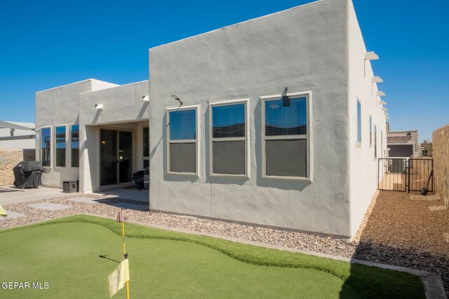 13436 Emerald Crystal Dr, El Paso, TX 79928 - back of house with an area to practice putting, stucco siding, and a patio area