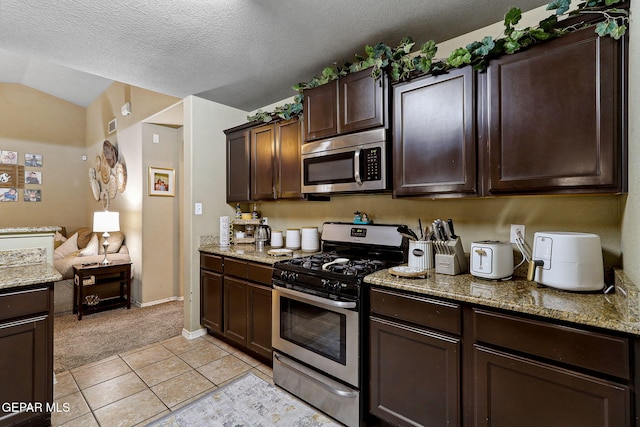 14196 Greg Allen, El Paso, TX 79938 - kitchen with appliances with stainless steel finishes, light colored carpet, dark brown cabinetry, vaulted ceiling, and light stone counters