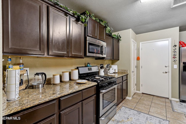 14196 Greg Allen, El Paso, TX 79938 - kitchen featuring appliances with stainless steel finishes, dark brown cabinets, light stone counters, a textured ceiling, and baseboards
