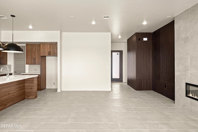 832 Acton St, Horizon City, TX 79928 - kitchen featuring light tile patterned floors, light countertops, a sink, decorative light fixtures, and brown cabinets