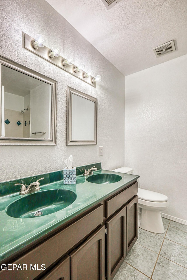 12044 Banner Crest Dr, El Paso, TX 79936 - full bathroom with double vanity, toilet, a textured wall, a textured ceiling, and tile patterned flooring
