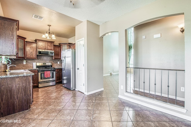 11352 Bullseye St, El Paso, TX 79934 - kitchen with stainless steel appliances, a sink, dark stone counters, backsplash, and arched walkways