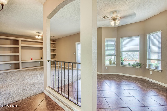 11352 Bullseye St, El Paso, TX 79934 - hallway with a textured ceiling, built in features, tile patterned floors, arched walkways, and baseboards