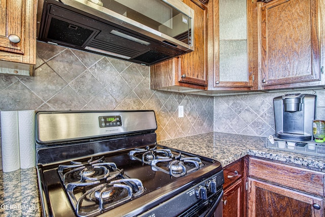 11352 Bullseye St, El Paso, TX 79934 - kitchen with gas stove, backsplash, glass insert cabinets, and brown cabinets