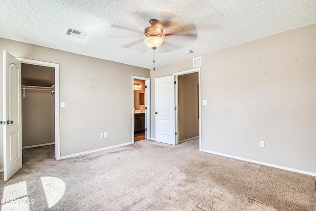 11352 Bullseye St, El Paso, TX 79934 - unfurnished bedroom with carpet, a walk in closet, baseboards, and a textured ceiling