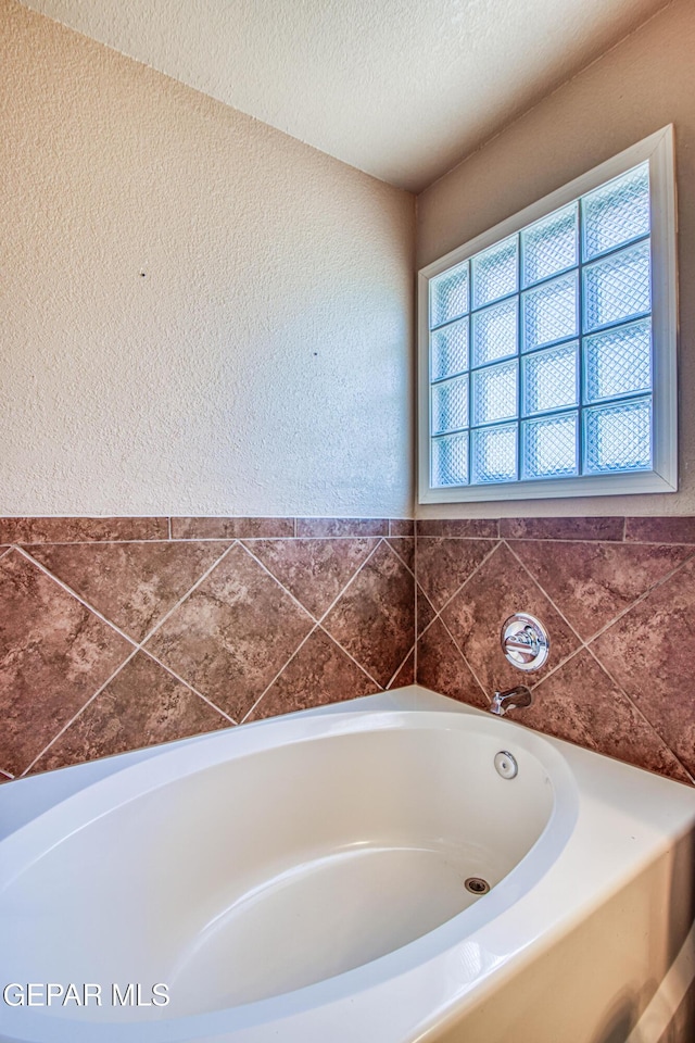 11352 Bullseye St, El Paso, TX 79934 - bathroom featuring healthy amount of natural light, a bath, a textured wall, and a textured ceiling