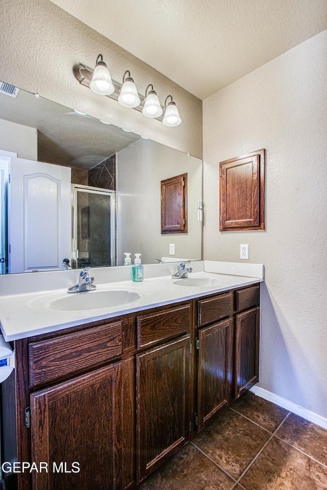 11352 Bullseye St, El Paso, TX 79934 - bathroom with double vanity, a stall shower, tile patterned floors, a textured ceiling, and baseboards